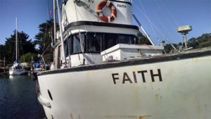 Photo of a black and white fishing boat that is names "Faith"